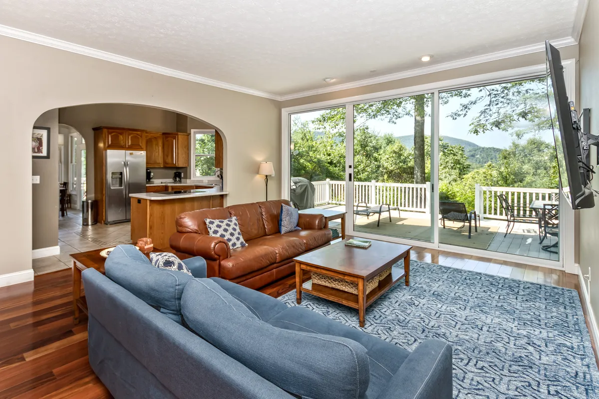 A cozy living room featuring a comfortable seating arrangement centered around a coffee table, with large windows that frame a breathtaking view of the mountains. Soft, neutral-toned décor and plush furnishings create a welcoming environment ideal for relaxation and gatherings.
