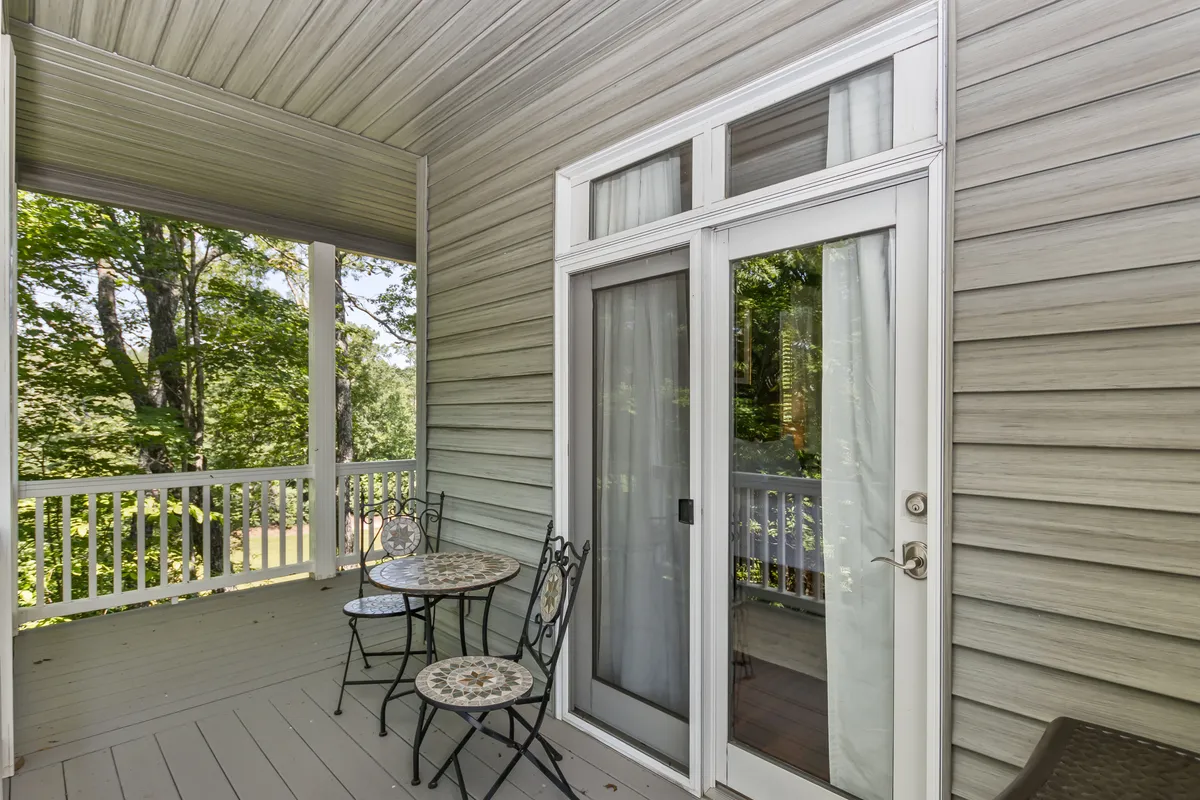A cozy balcony with a small round mosaic table and two ornate chairs sits just outside sliding glass doors. The setting is ideal for sipping tea, reading, or unwinding while soaking in mountain breezes and sunset views.