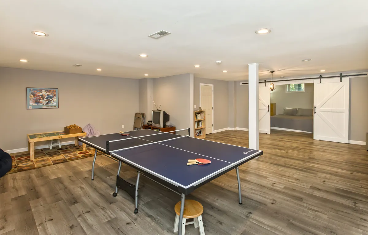 An energetic and fun playroom area with a ping pong table, sliding barn doors, and colorful artwork on the walls. This flexible recreational space is ideal for kids, teens, or night owls to unwind and play.