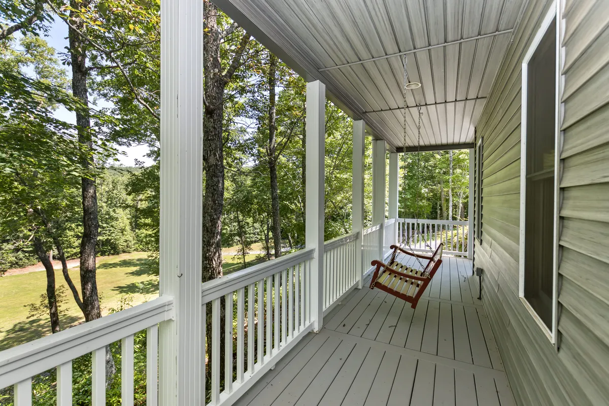 A rustic wooden deck features rocking chairs overlooking a forested landscape. The tranquil scene is designed for relaxing, wildlife watching, and soaking in the natural beauty after a day spent exploring the mountains.