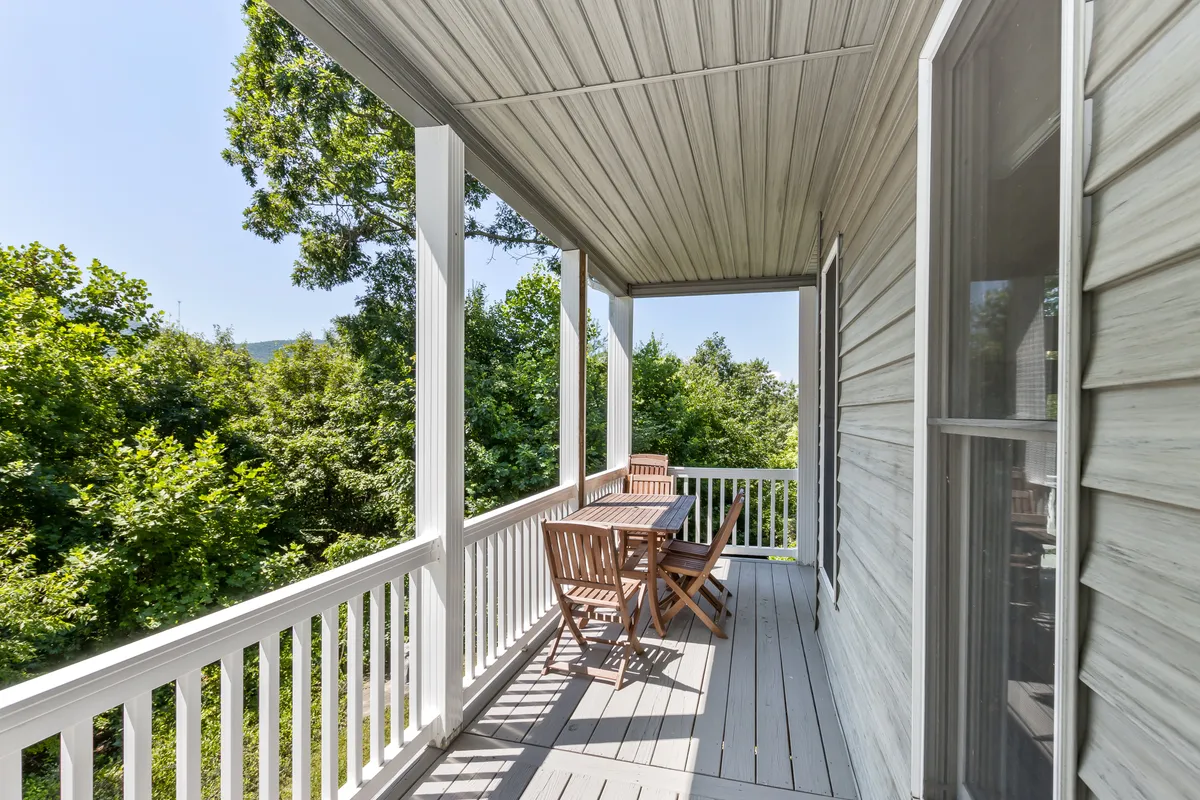 This image displays an outdoor dining area surrounded by green foliage, featuring a sturdy wooden dining table and matching chairs. Warm sunlight bathes the space, hinting at lively mornings, sunset gatherings, and starlit evenings immersed in nature.
